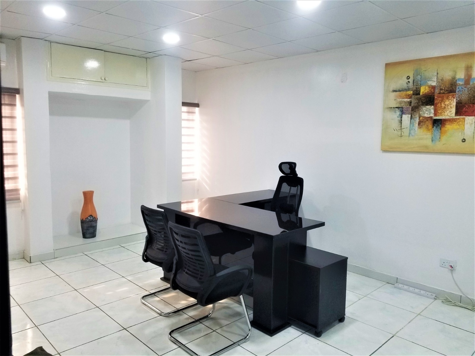 Office with black desk, yellow sofa, and art on the wall