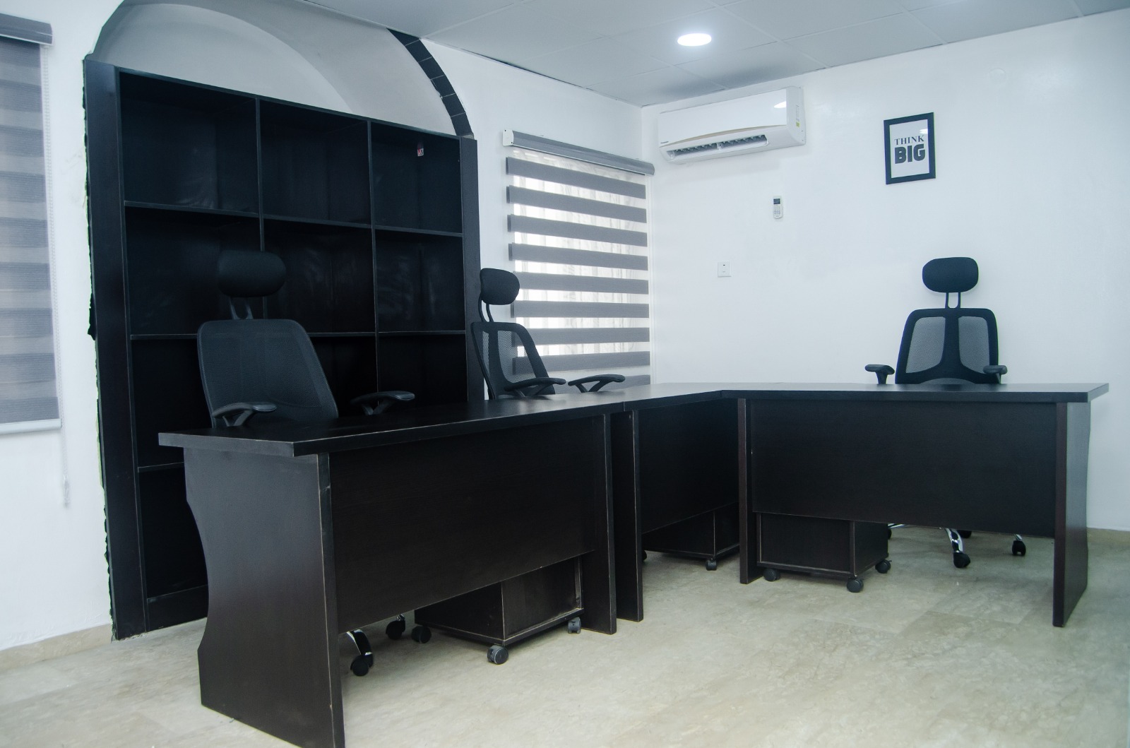 Three-desk office with blinds and black furniture