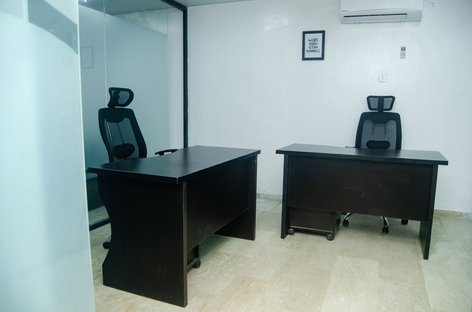Two-desk office with glass partition and minimalist decor